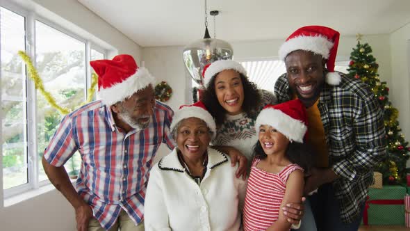 Happy african american multi generation family wearing santa hats, taking holiday photo