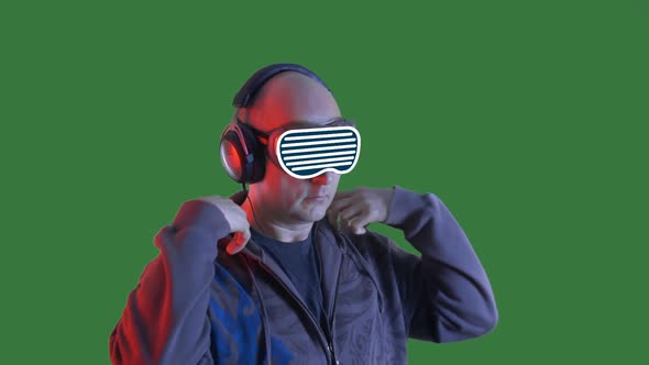 Bald Man Listening Music in Headphones and VR Glasses on Green Chromakey Background, Man in Black