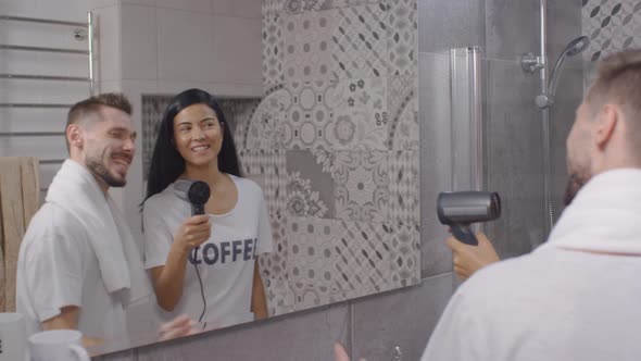 Young Couple Singing with Blow Dryer in Bathroom