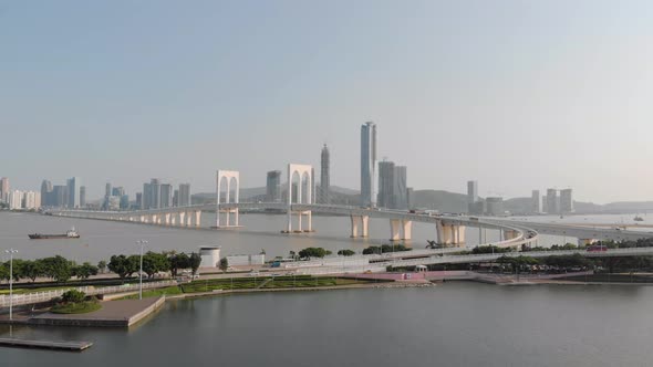 Drone approach shot of traffic crossing Sai Van Bridge in Macau with mainland China skyscrapers in b