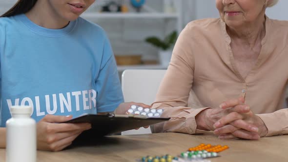 Attentive Female Volunteer Helping Old Lady to Choose Prescribed Medicine, Care