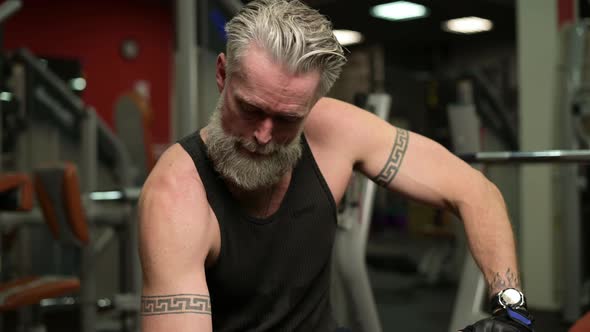 tattooed man doing a hard workout in the gym and pumping up the biceps