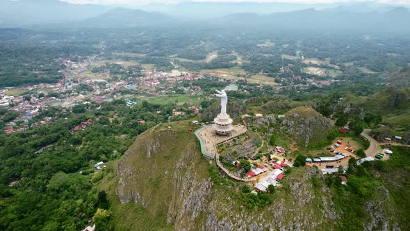 Aerial of a Jesus Christ Statue in Tana Toraja Sulawesi at the top of a mountain with tourists and s