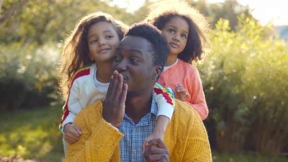 Portrait of African Father and Adorable Little Daughters Blowing Air Kisses and Smiling at Camera