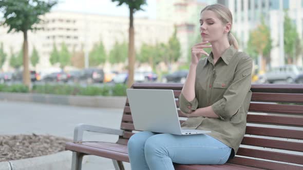 Thinking Woman Using Laptop while Sitting Outdoor on Bench