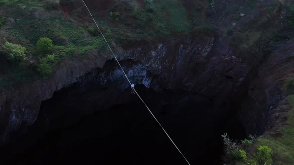 Slackliner Is Sitting on a Massive Rope Over the Scary Huge Pit