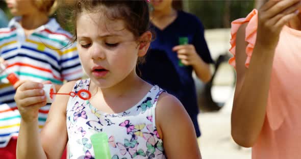 Schoolgirl playing with bubble wand in playground