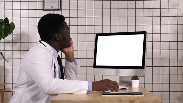 Young african doctor looking on monitor of his computer.