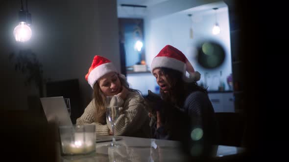 Two Beautiful Young Women in Christmas Hats Taking a Video Call on a Laptop