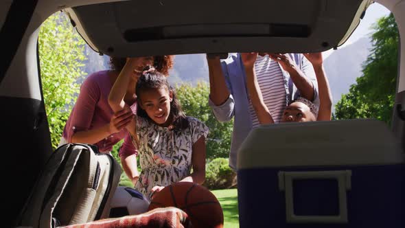 Happy african american parents,son and daughter, openieng car trunk with picninc supplies