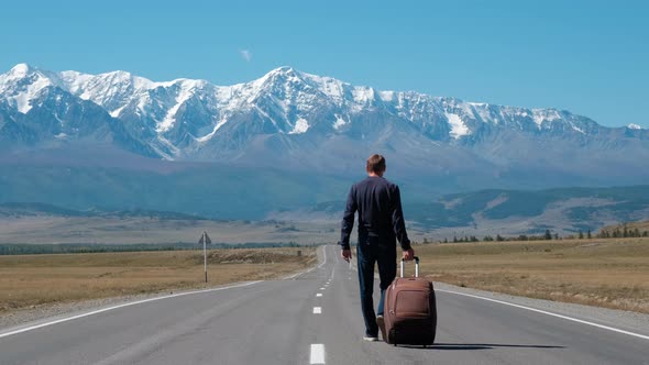 Man with Suitcase Traveling on Mountain Road