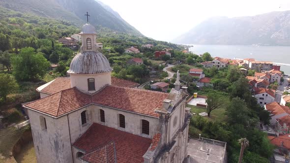 Ancient Church in the Town of Prcanj Against the Backdrop of Greenery and Old Houses