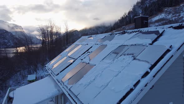 Solar panels on private home covered in snow - Smoke from chimney with stunning fjord landscape back