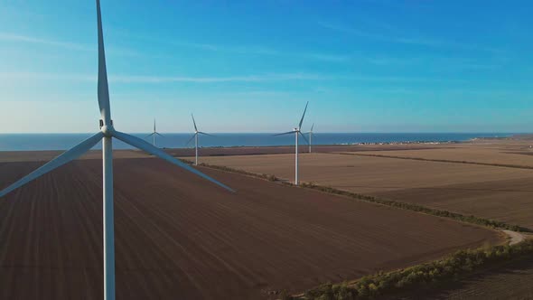 Aerial View of Autumn Countryside with Wind Turbines and Agricultural Fields on Sea Coast Background