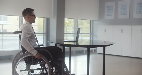 Positive Disabled Young Man in Wheelchair Working in Office