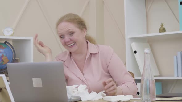 Portrait of Senior Woman Laughing Out Loud As Sitting at the Table with Pile of Used Tissues