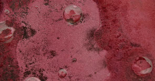 macro shot of a red viscous liquiding form left and right to the center. drops of gel on the surface