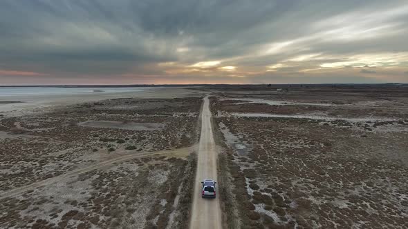 Car Going on Dirt Road on Flat Terrain at Sunset. Finish and The End