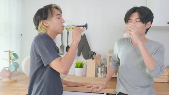 Asian handsome man gay family hold a cup of wine, celebrate anniversary party in kitchen at home.