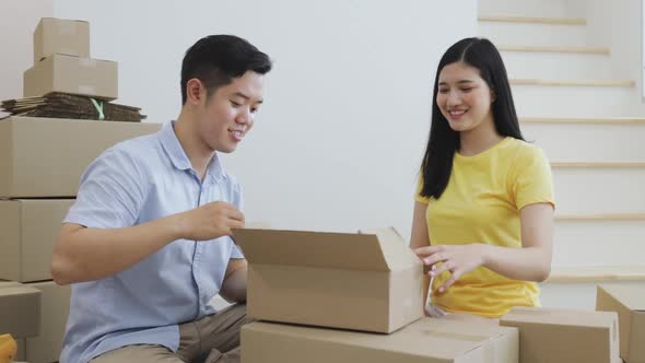 Happy Couples while unpacking carton box together and surprise with gift inside carton box