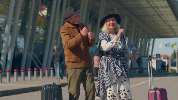 Senior Husband Wife Retirees Tourists Go to Airport Terminal for Boarding with Luggage on Wheels