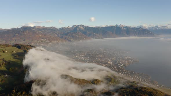 Aerial of patch of fog climbing and dissipating fast over forest and farm fields. Montreux, Vevey an