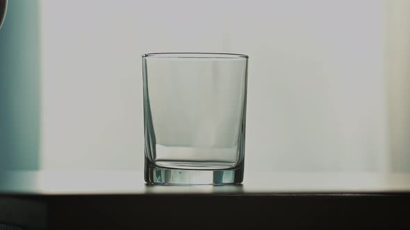 A Stream of Clear Transparent Cold Water is Poured Into a Glass