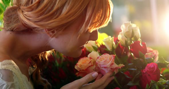 Beautiful female florist smelling pink rose