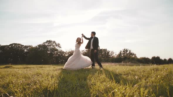 Happy Wedding Couple Walks and Whirls on Beautiful Nature