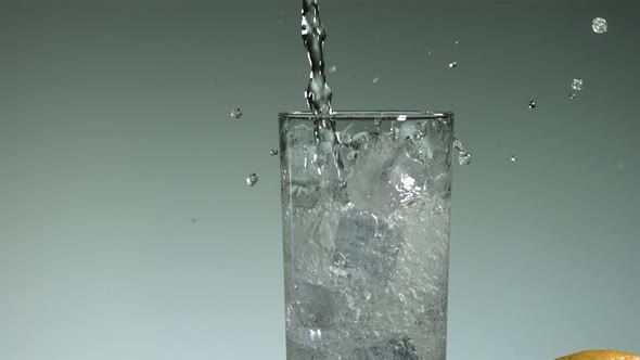 Carbonated liquid pouring into glass filled with ice 