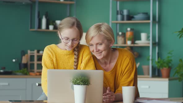 Caring Mom and Teenage Girl Doing Homework Together Using Laptop