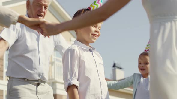 Family Dancing and Celebrating Birthday of Little Boy Outdoors