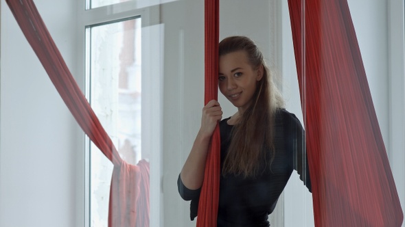 Young female pole dancer standing near to a aerial fabric