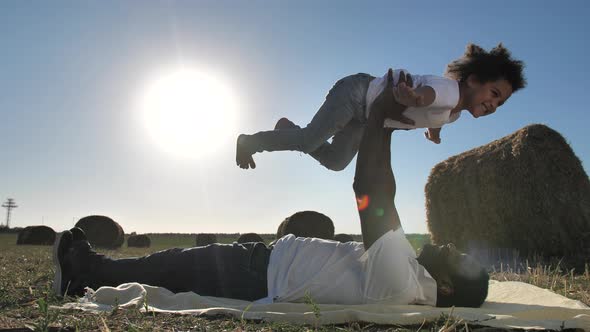 Happy Curly Girl Flying on Daddy's Arms Outdoors