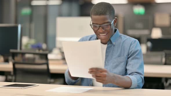 Young African American Man Celebrating While Reading Documents