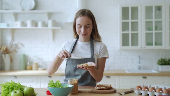 Happy Smiling Woman in the Kitchen Preparing a Peanut Butter Sandwich