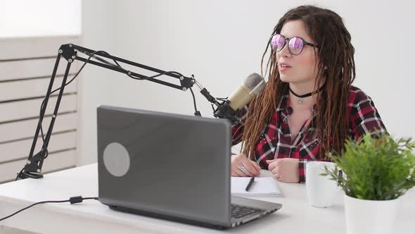 Concept of Streaming and Broadcasting. Young Woman in the Studio Speaks Into a Microphone