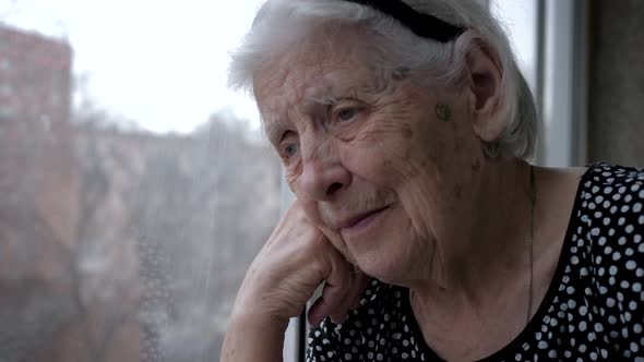 Thoughtful Old Elderly Caucasian Woman With Gray Hair Looking Sadly Out Window