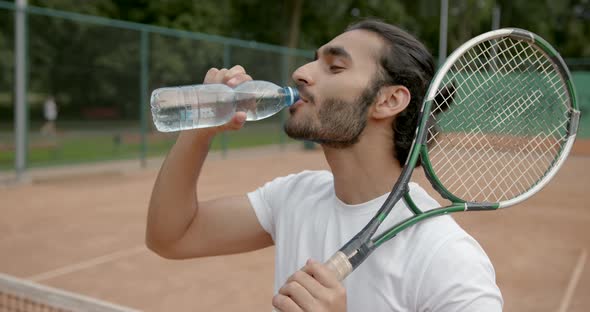 Handsome Tired Tennis Player with Water on Tennis Court