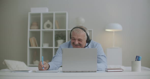 Cheerful Man Is Chatting with Colleagues By Video Chat on Laptop During Daily Online Meeting and
