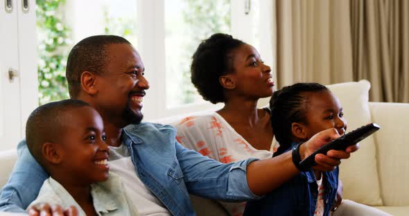 Parents and kids having fun while watching television in living room