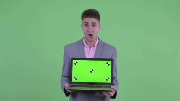 Happy Young Businessman Showing Laptop and Looking Surprised