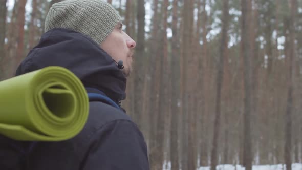 Young man hiker photographer with backpack taking a picture in winter forest. Slow motion