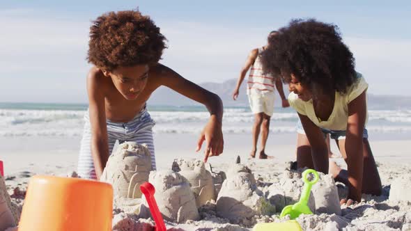 African american brother and sister playing with sand on the beach