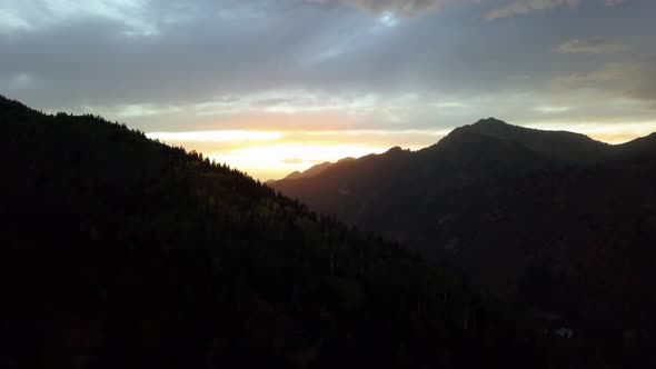 Aerial drone view of a beautiful fall sunset with the sun gleaming over the mountain timberline in t