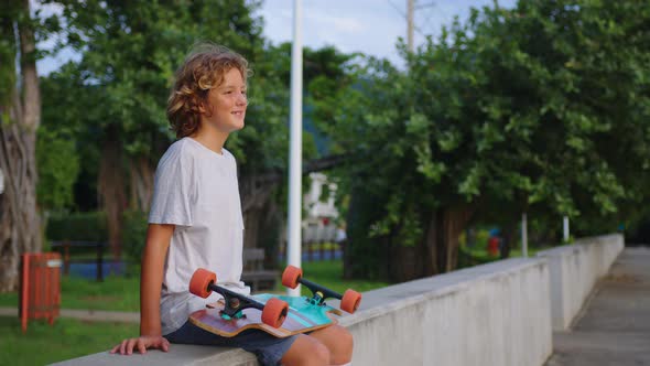 Happy Teenager Stylish Skater Boy Holding His Skateboard Outdoors