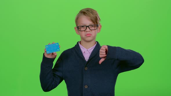 Child Boy in Glasses with a Credit Card Shows Dislike and Then Like on a Green Screen