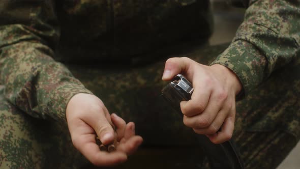 A Russian Military Man Loads Cartridges Into the Magazine of a Kalashnikov Assault Rifle  Closeup