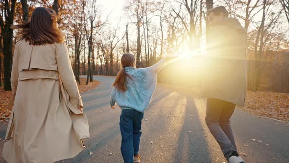 Young Parents Running with Little Daughter Holding Red Toy Plane