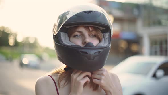 Beautiful Young Redhaired Woman Motorcyclist Removes Helmet on Sunset